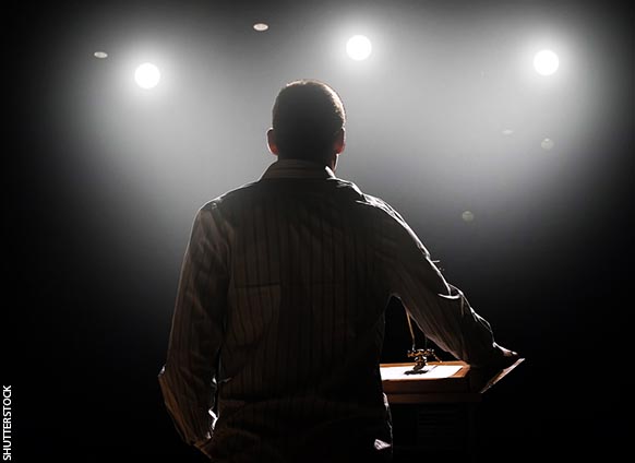man speaks at an event in a dark hall